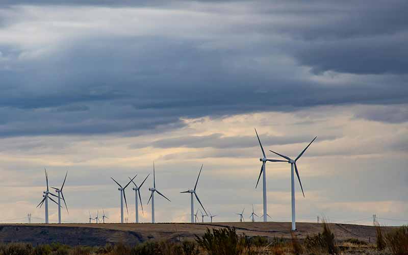 Wind turbines in a flat field with a cloudy sky above