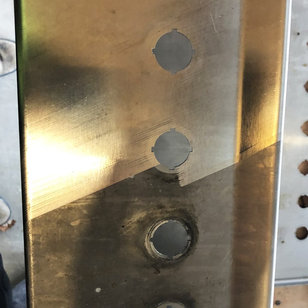 A piece of metal, half of which is shiny after being cleaned with a laser machine